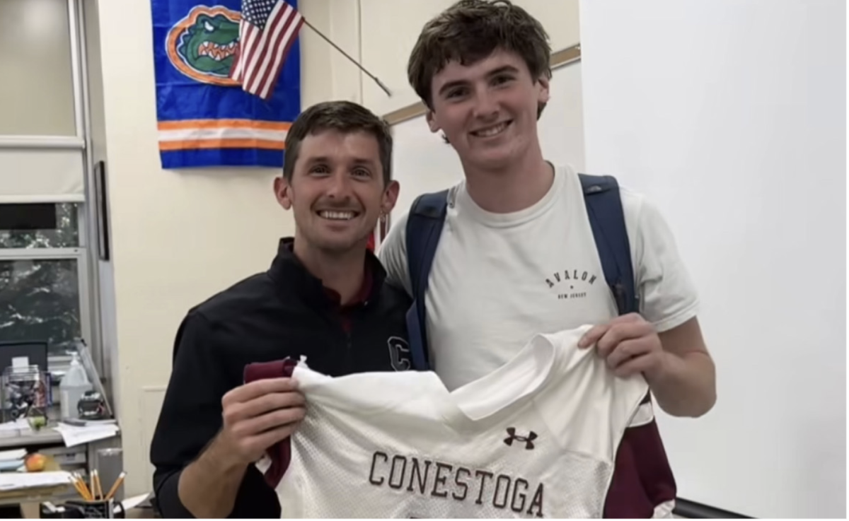 Your impact: Senior Landon Ross and teacher Brian Gallagher pose with Ross’ jersey. The football team started the “My Jersey, Your Impact” initiative this fall.